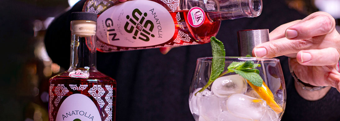 Full colour gin labels on clear material with white underprint. IMage shows person pouring gin into a measure over a gin glass.